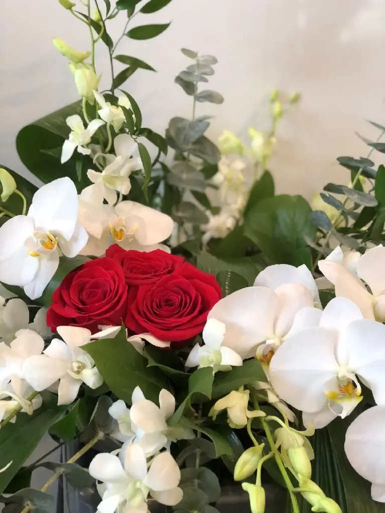 À jamais dans nos cœurs – accompagnement d’urne avec orchidées blanches, cœur de roses rouges, eucalyptus et feuillage à Montréal.2.webp