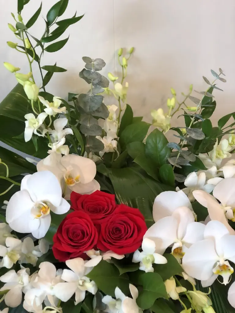 À jamais dans nos cœurs – accompagnement d’urne avec orchidées blanches, cœur de roses rouges, eucalyptus et feuillage à Montréal.1.webp
