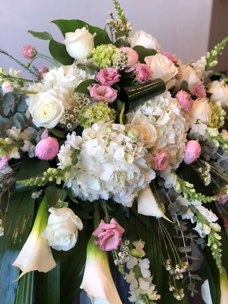 Tendre adieu – coussin de cercueil blanc et rose avec hydrangées, roses crème, callas, eucalyptus et fleurs délicates à Montréal.1.webp