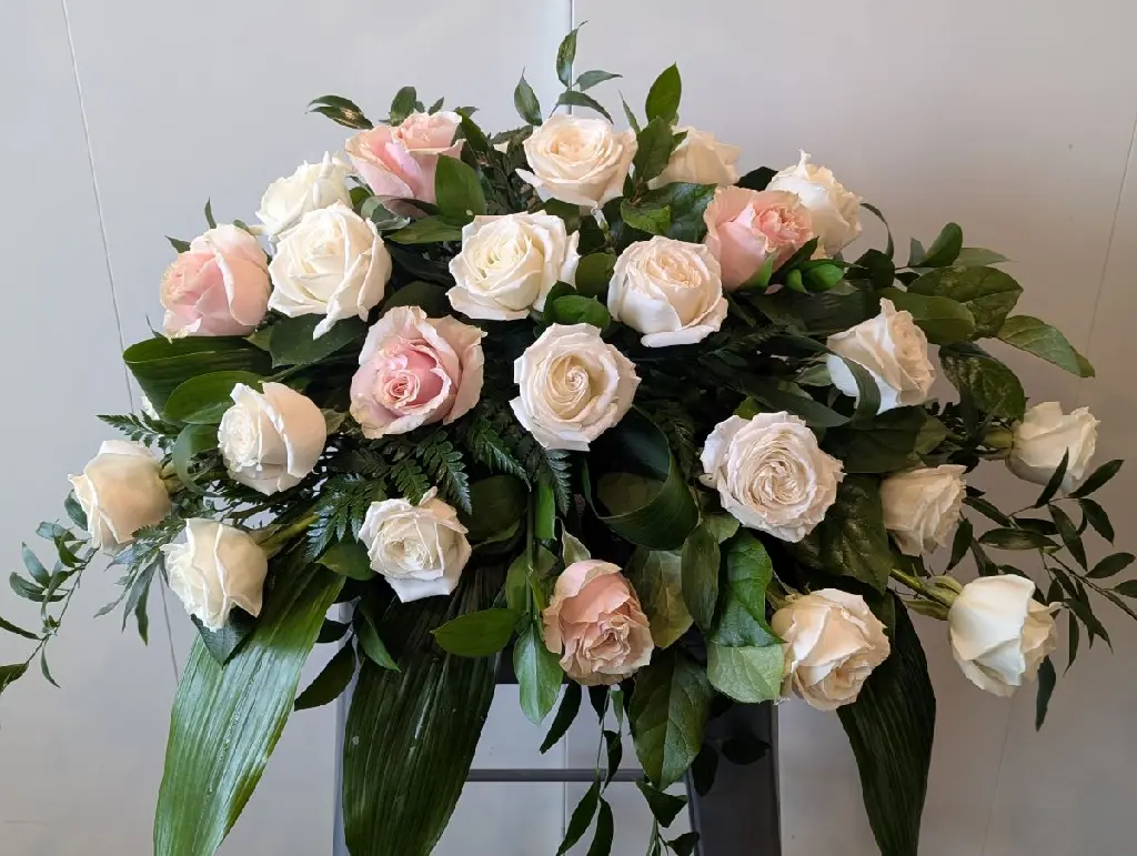 Coussin de cercueil composé de roses roses et blanches. Hommage floral classique et délicat confectionné à Montréal avec livraison funéraire..1.webp