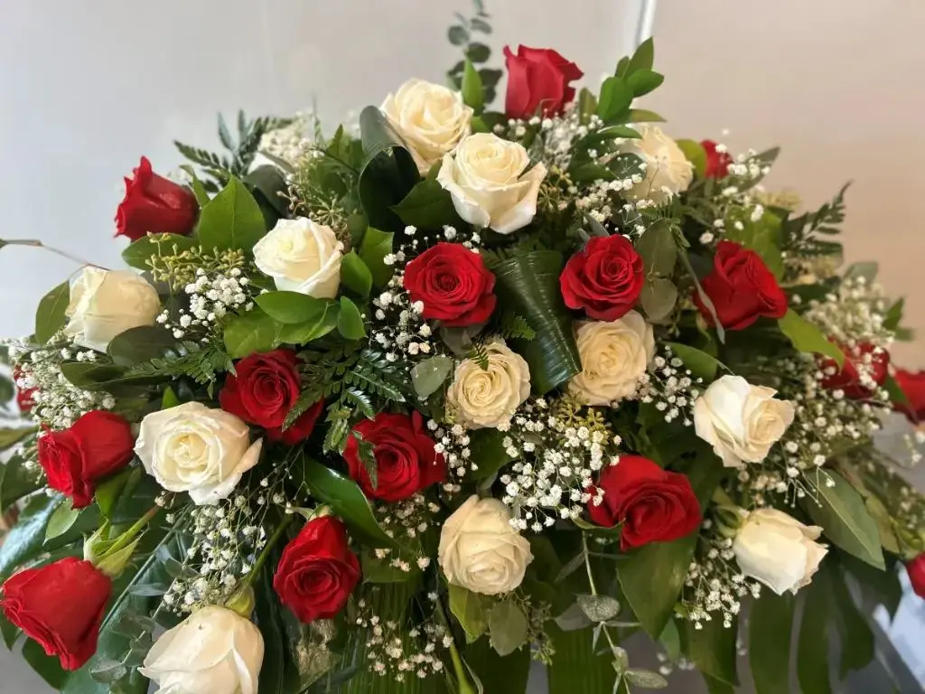 Pour toujours – coussin de cercueil composé de roses rouges et blanches, gypsophile et feuillage vert à Montréal.1.webp