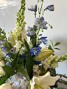 Composition florale blanche et bleue avec lys blancs, hortensias bleu pâle, delphiniums et feuillages, créée par La Maison d’Alcantara à Montréal.webp