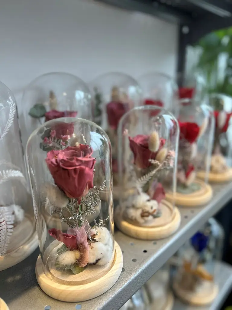 Rose rouge éternelle sous cloche de verre avec végétaux séchés sur socle noir à Montréal.1.webp