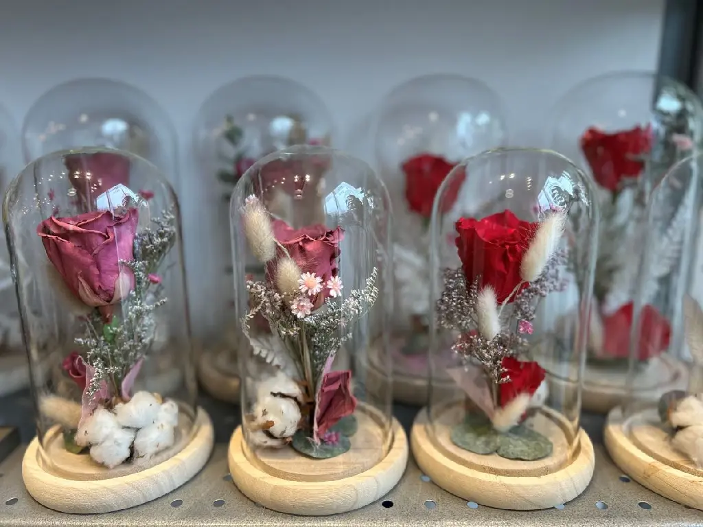 Rose rouge éternelle sous cloche de verre avec végétaux séchés sur socle noir à Montréal.2.webp